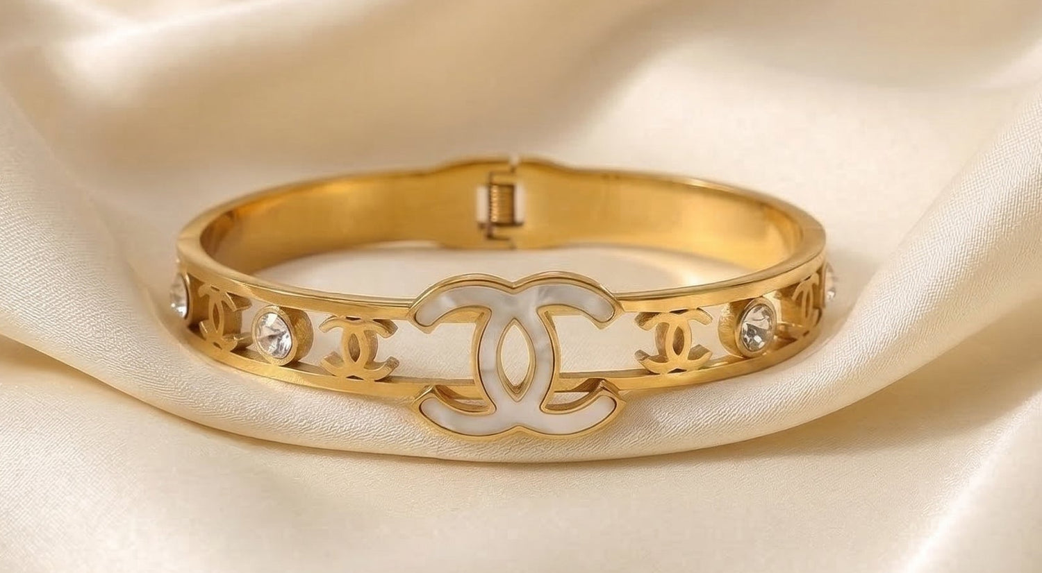 Gold bracelet with diamond accents on a beige satin background